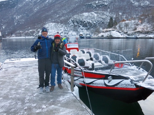 Planetski editor standing beside a launch by a Norwegian lake with snow on the shoreline